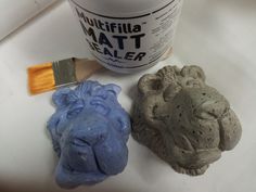 three clay animals next to a paintbrush on a white counter top, one is blue and the other is brown