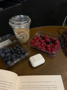 an open book sitting on top of a table next to berries and yogurt