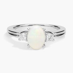 a white opal and diamond ring with three stones on the side, set in 18k white gold