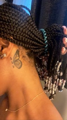 the back of a woman's head with braids and butterfly tattoos on it