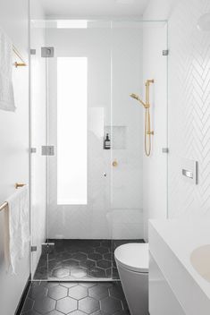 a bathroom with black and white tile flooring, gold faucet, and shower