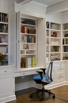 a home office with white bookcases and blue chair