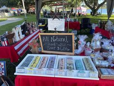 an assortment of desserts are on display for sale at the outdoor market with red and white tables