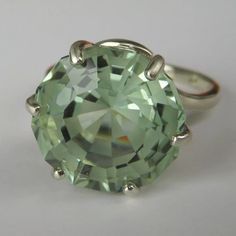 an oval cut green amethorate ring on a white surface with silver accents