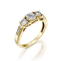 three stone diamond ring in yellow gold with diamonds on the sides and shoulders, set against a white background