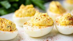 deviled eggs with mustard sprinkled on them sitting on a white platter