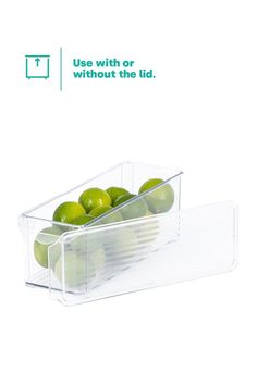 a plastic container filled with green apples sitting on top of a white table next to an advertisement