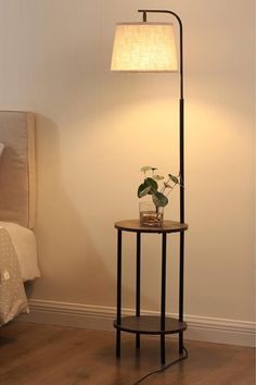 a lamp that is on top of a table next to a bed in a room