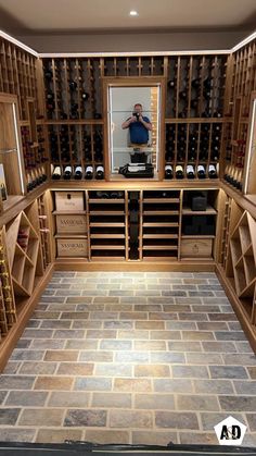 a man taking a selfie in the mirror of a wine cellar filled with bottles