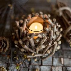 a candle that is sitting in some kind of bowl with wood sticks on the ground