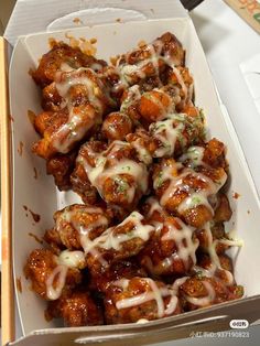 a white box filled with meat covered in sauce and cheese next to chopsticks