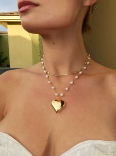 Make a statement with this elegant 18k gold heart pendant! Featuring a pearl chain for added sophistication. Made with 18k plated gold over stainless steel.  Length: 16.5 in with a 2 in extender chain Pendant Width: 30mm Statement Necklace Aesthetic, Gold Heart-shaped Pearl Pendant Jewelry, Gold Pearl Jewelry With Heart Charm, Gold Pearl Jewelry With Heart Beads, Gold Necklace With Pearl Chain For Valentine's Day, Gold Pearl Necklace With Heart Pendant And Beads, Valentine's Day Gold Necklace With Pearl Chain, Valentine's Day Heart Pendant Necklace With Pearl Chain, Valentine's Day Gold Pearl Chain Necklace