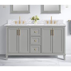 a bathroom vanity with two sinks and gold faucets on the top, in front of mirrors