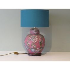 a pink vase sitting on top of a table next to a blue lampshade