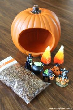 an orange pumpkin sitting on top of a wooden table next to other halloween decorations and candy