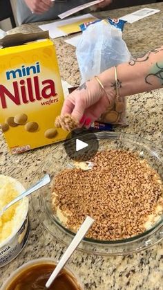 someone is making a pie with nuts on the crust and toppings in bowls next to it