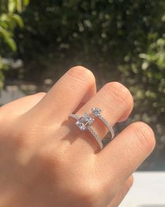 a woman's hand holding an engagement ring with two diamonds on top of it