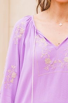 Float into the season with this beauty in your possession! This top was crafted with tassel ties and delicate embroidery detailing, that will transport you to a world of relaxation and style! The flowy fit provides comfort and versatility, while the pretty lavender color adds a touch of flair to your style! 100% Rayon Lavender V-neck Top For Vacation, Lavender Beach Tops For Spring, Lavender Tops For Beach In Spring, Lavender Spring Beach Top, Spring Vacation Purple Blouse, Lavender Long Sleeve Bohemian Tops, Purple Bohemian Top With Floral Embroidery, Bohemian Purple Top With Floral Embroidery, Bohemian Purple Blouse For Spring