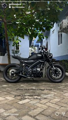 a black motorcycle parked in front of a blue building with a quote written on it