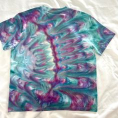 a t - shirt that has been dyed with different colors and patterns on it, sitting on a white sheet