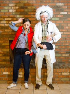 two people standing next to each other in front of a brick wall and wearing costumes