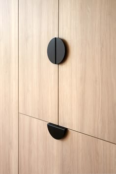 two black round knobs are on the side of a wooden cabinet with wood grained doors