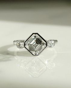 a diamond ring sitting on top of a white surface with three diamonds around the band