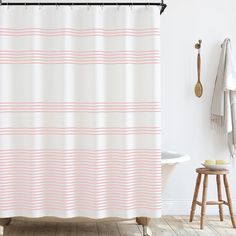 a white shower curtain with pink stripes on it in a bathroom next to a stool