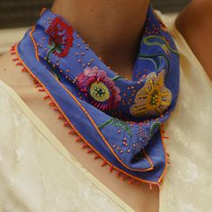 Periwinkle Bandana with Multi-Colored Flower Embroidery Styled on Model's Neck Bohemian Scarves For Weddings And Festivals, Blue Bohemian Silk Scarf For Spring, Bohemian Blue Silk Scarf For Spring, Blue Bohemian Embroidered Scarves, Festive Embroidered Silk Scarves, Spring Traditional Silk Scarf, Bohemian Silk Scarf For Summer, Bohemian Silk Scarf, Multicolor Embroidered Bohemian Scarves