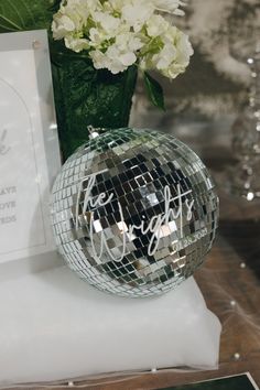 a disco ball sitting on top of a table next to a vase filled with flowers