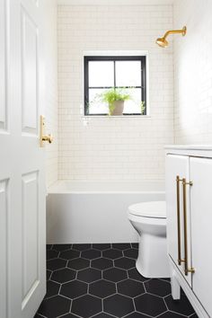 a white toilet sitting next to a bath tub in a bathroom with black and white tile