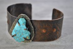 "Handcrafted rustic copper cuff created by hammering, annealing, form folding, drilling, filing, and adding an antique patina. A rough cut turquoise  stone has been attached through the use of prongs The piece has been tumbled for polishing. The inside of this bracelet has been treated with acrylic to prevent tarnish on your skin.  I love making these bracelets and hope you will enjoy wearing one too! INSIDE FIT:  The inner circumference is 6\" with a 1\" gap  This cuff would be considered a medium size. 1 1/4\" wide   3.17 cm  Sizing: Cuffs have approximately a 1\" - 1 1/4\" opening and this can be adjusted either way with slight pressure for your custom fit. This allows you to use the gap in the bracelet for putting on and taking off.  Your cuff will be placed in a gift box with a cotton Hand Forged Turquoise Brass Jewelry, Artisan Hand Cast Adjustable Jewelry, Rustic Turquoise Bracelet Jewelry, Rustic Turquoise Bracelet, Hand Forged Rust Copper Jewelry, Rust Colored Hammered Copper Jewelry, Vintage Adjustable Hammered Jewelry, Bronze Bohemian Jewelry With Patina, Adjustable Vintage Hammered Jewelry