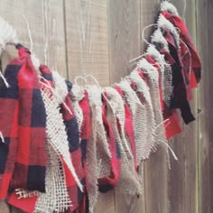 red, white and black plaid fabric hanging from a wooden fence with string attached to it