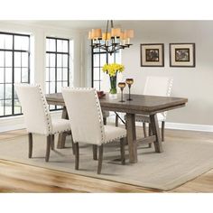 a dining room table with white chairs in front of it and yellow flowers on the table