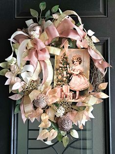 a wreath is hanging on the front door with pink and white flowers, an angel ornament, and pictures