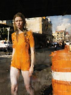 a woman in orange is standing next to an orange traffic cone