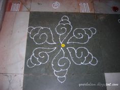 an intricate design is drawn on the ground with white chalk and yellow dot in center