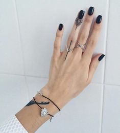 a woman's hand with black and white nail polish holding onto a diamond bracelet