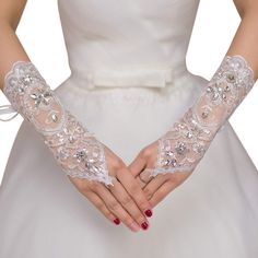 a woman in a wedding dress holding out her hands with lace gloves on top of it