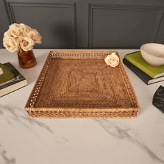 a wicker tray sitting on top of a white table next to flowers and books