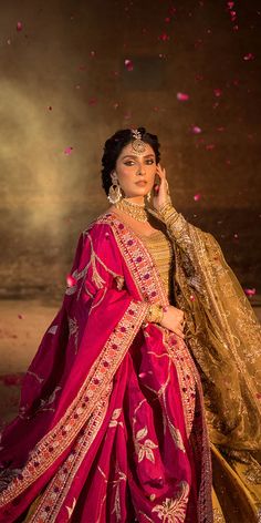 a woman in a red and gold outfit with pink petals around her neck, holding a cell phone up to her ear