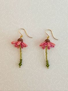 the earrings are decorated with pink flowers and green beads