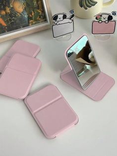 three pieces of pink plastic sitting on top of a table next to a cup and mirror