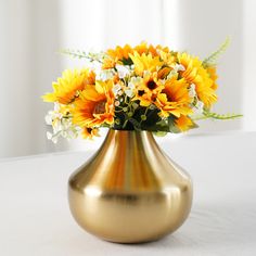 a gold vase filled with yellow and white flowers