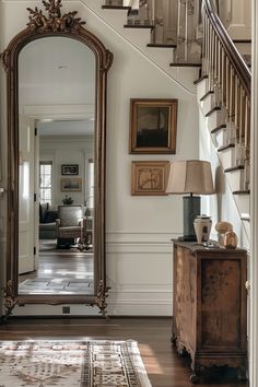 a large mirror sitting on top of a wooden table next to a stair case in a living room