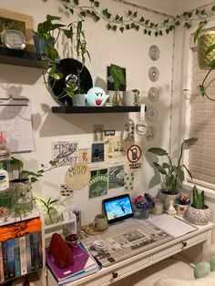 a desk with a laptop computer sitting on top of it next to a plant filled wall