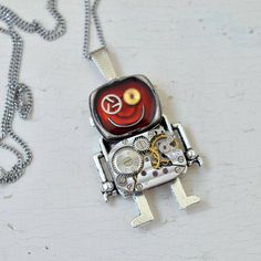 "Watch Parts Red Robot Pendant. Steampunk Necklace. Robot Pendant. Android Necklace. Red Android. Industrial gift. Fancy necklace. Robot lovers gift. Robotic gift. Handmade steampunk red resin necklace. Watch parts are carefully cleaned and embedded crystal resin in robot pendant, on the blue red. The eco-friendly resin (derived from tree sap) is crystal clear, allowing you to see many different types of watch part from cogs. A unique piece suited to the steampunk. ROBOT is unique, never the sam Retro Metal Jewelry For Gifts, Retro Metal Jewelry For Gift, Novelty Nickel-free Pendant Necklace, Nickel-free Novelty Pendant Necklaces, Nickel-free Novelty Pendant Necklace, Red Retro Metal Jewelry, Retro Red Metal Jewelry, Retro Charms Necklace Gift, Retro Charms Necklace For Gift