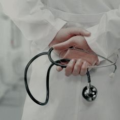 a person in white coat holding a stethoscope with both hands on their chest