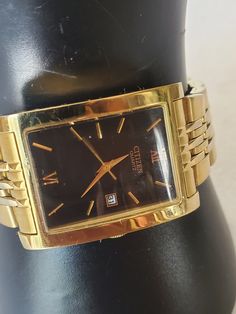 This listing is for a vintage gold tone rectangular shaped Men's Citizen Quartz watch. It has a black face and elegant gold hands and 2 numbers: 12 and 6. There is a date slot that is sent at date 31. This watch came from an estate sale in Thornton, Co. and runs great just needed a new battery. It did not come with the original box but will be send out in a gift box with FREE SHIPPING. I will measure the bezel and band for a good fit. There is some metal wear on the Citizen closure nothing too bad I tried to take close photos so you can see look at photo #7 if this is an issue, please reframe from buying.  Bezel Measure: 1 1/4"L X 1 1/8"W Band measures: 8"L including bezel X 3/4"W Material: gold tone metal, stainless steel fold over band and bezel, rectangular gold tone bezel, black face, Gold Rectangular Watch Accessories For Formal Occasions, Gold Square Watch For Formal Occasions, Classic Gold Square Watch Accessories, Gold Rectangular Watches With Subdials, Gold Square Analog Watch, Gold Square Analog Watches, Gold Watches With Date Display And Rectangular Dial, Mens Gold, Gold Hands