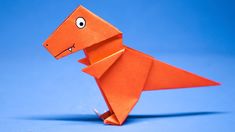 an orange origami dinosaur standing upright on a blue background with one eye open